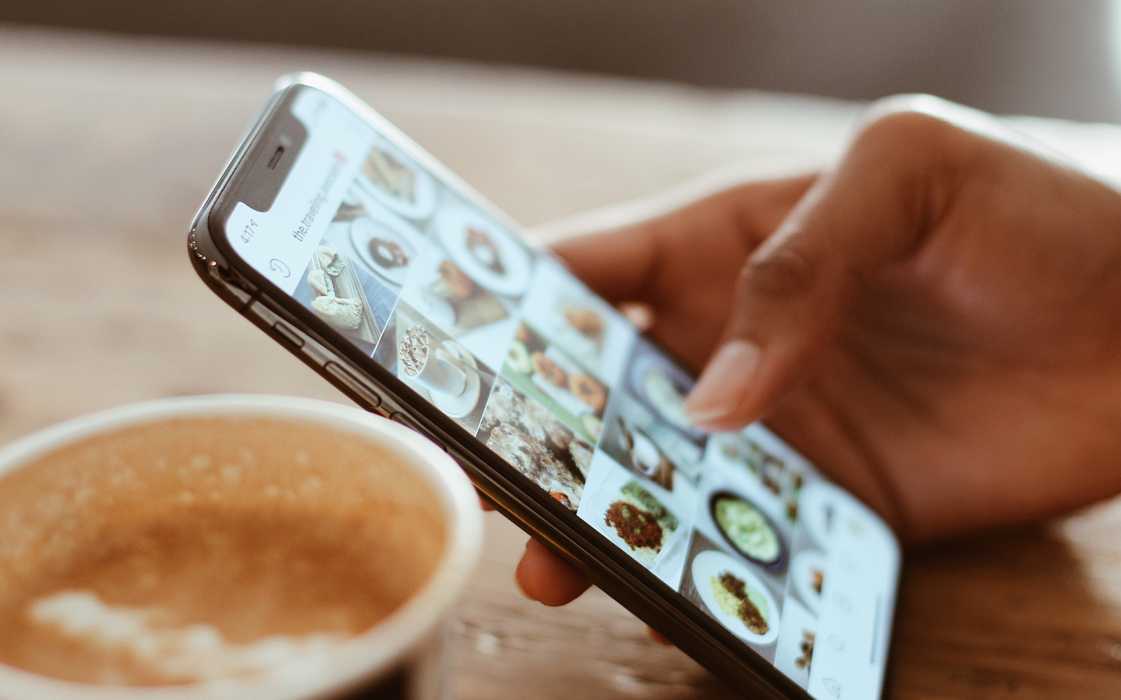 A hand holding a phone with photos open. 